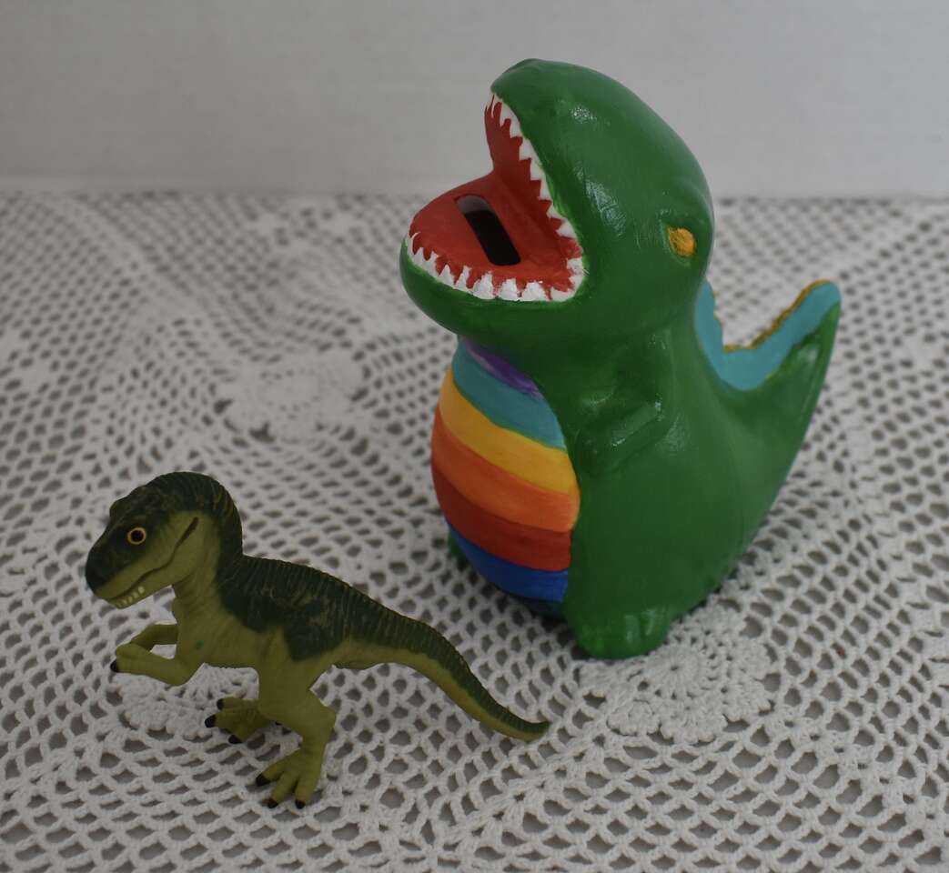 Two Dinosaur Items - One Small Plastic Dinosaur Toy And Also A Small Hand Painted Dinosaur Bank