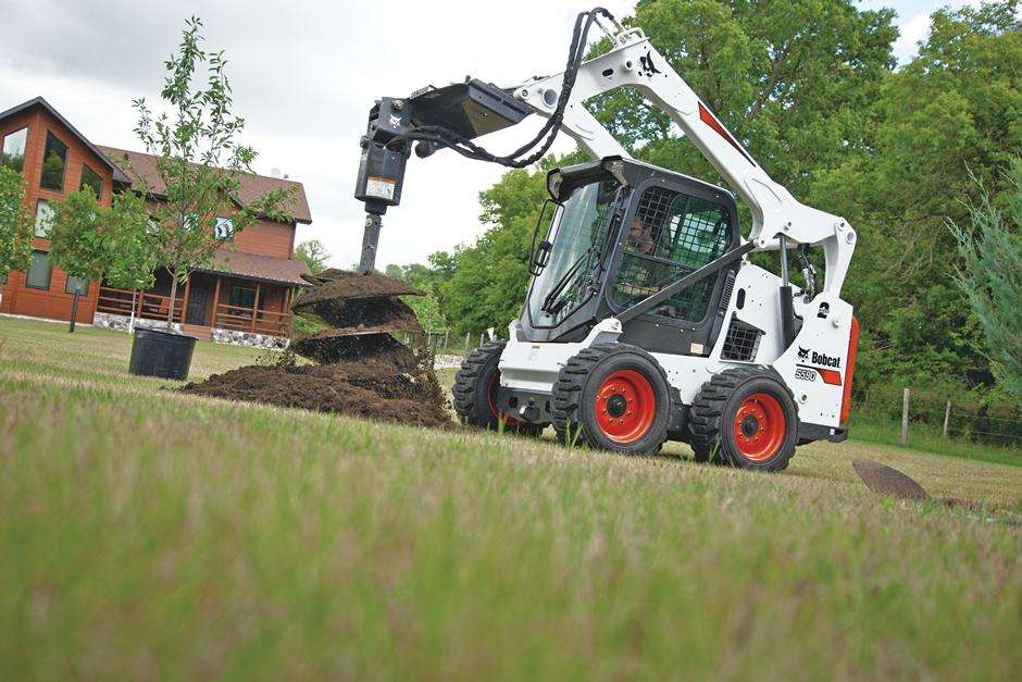 Bobcat skid steer with auger. Also available with forks, grapple, rock bucket, concrete breaker