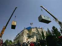 Jewish settler protesters hold poles to delay Israeli troops being lowered in a shipment container onto a rooftop of a fort where settlers barricaded themselves to resist forced evacuation, in the Jewish settlement of Sanur in the northern West Bank Tuesday Aug. 23, 2005. Riot troops with shields on Tuesday stormed a barricaded rooftop where the last holdouts against the evacuation of this West Bank settlement had holed up.