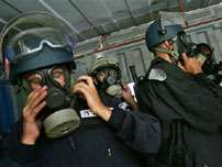Israeli riot police wear gas masks before they were lowered in a shipment container onto a barricaded rooftop, during the evacuation of the Jewish settlement of Sanur, in the northern West Bank, Tuesday Aug. 23, 2005.