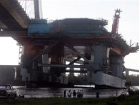 People gather to watch an oil rig that broke apart in drydock during Hurricane Katrina and is stuck on the Cochrane-Africatown USA Bridge over the Mobile River Tuesday Aug. 30, 2005, in Mobile, Ala.