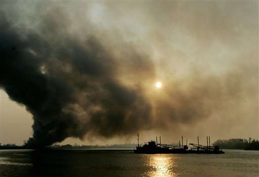 A U.S. Coast Guard vessel heads south on the Mississippi River past a fire on the east side of New Orleans, La., early Friday, Sept. 2, 2005. In the aftermath of Hurricane Katrina, firefighters say they will let the fire burn itself out. (AP Photo/Eric Gay)
