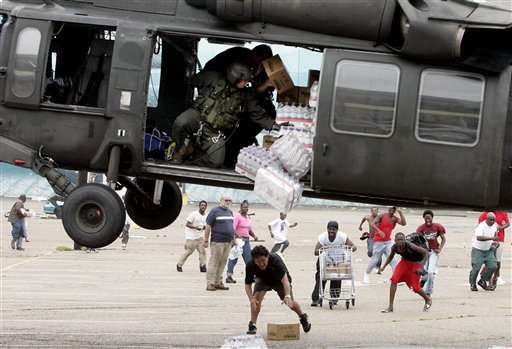A military helicopter makes a food and water drop to survivors of Hurricane Katrina near the Convention Center in New Orleans, Thursday, Sept. 1, 2005. (AP Photo/Eric Gay)