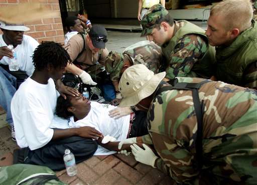 Military troops give aid to an injured woman on the sidewalk near the Convention Center in downtown New Orleans on Friday, Sept. 2, 2005. A huge military presence has arrived in the city, restoring order and bringing with them food and water to feed the thousands of victims of Hurricane Katrina. (AP Photo/Dave Martin)