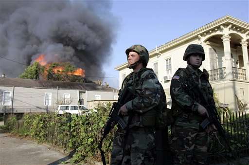 Two soldiers stand guard as firefighters battle a house fire in the lower Garden District of New Orleans, Tuesday, Sept. 6, 2005. Several fires broke out in the downtown area Tuesday. (AP Photo/Eric Gay)