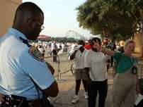 A survivor of Hurricane Katrina from New Orleans, right, flashes a peace sign as she passes Houston Police Department officer M.A. Wilson while wading through a line to get a debit card from FEMA at the Reliant Center in Houston on Friday, Sept. 9, 2005. The debit cards carry a balance of $2,000 for Katrina survivors.