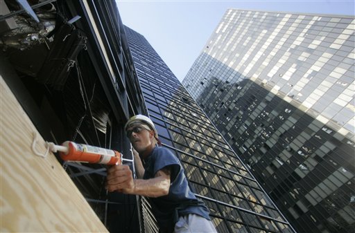John Scheidle, armed with a caulking gun, starts the process of boarding up windows blown out by Hurricane Katrina on downtown office towers in New Orleans on Monday, Sept. 12, 2005. (AP Photo/Rick Bowmer)