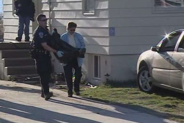 Officers carry one of the deceased dogs away from the residence.