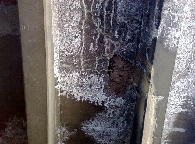 The underside of the bridge where chunks of concrete have broken off.