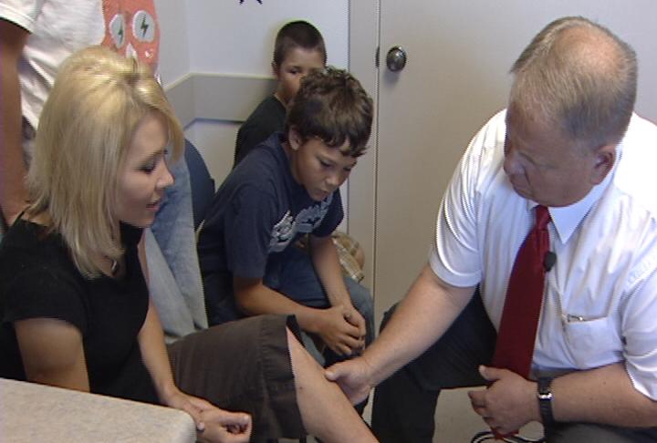 Dr. Rodney Anderson examines the wound on Keli Nielsen's leg.