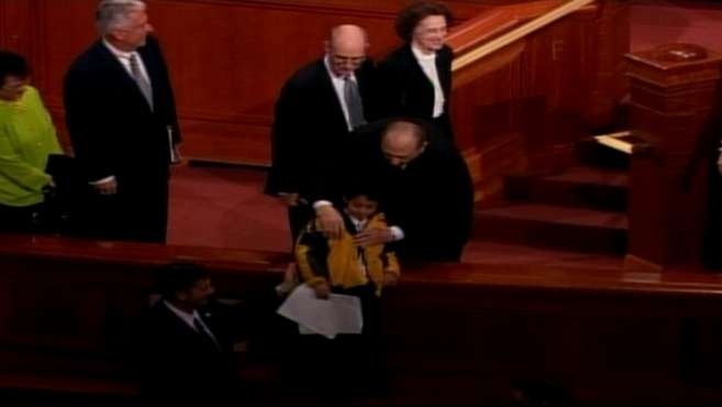 President Thomas S. Monson helps a young boy with his coat after the closing session