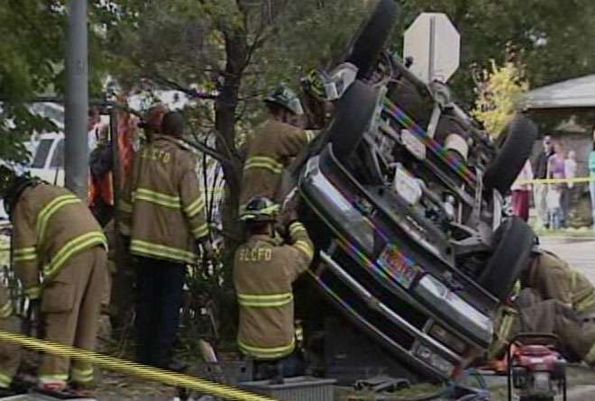 Firefighters work to get 19-year-old Christopher Bullock out of his SUV after it was hit by another car and rolled Monday