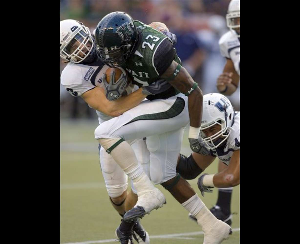Hawaii running back Leon Wright-Jackson gets pulled down by Utah State safety James Brindley, left, and DE Junior Keiaho during the first quarter Saturday, Nov. 7, 2009 in Honolulu. (AP Photo/Marco Garcia)