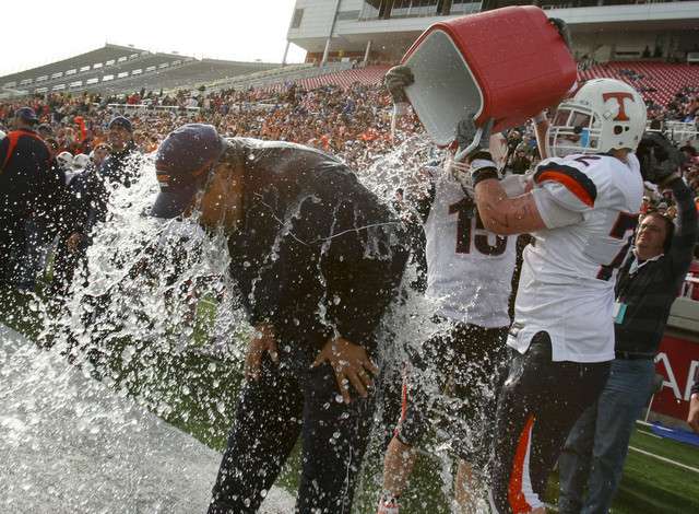 Timpview's Alex Moon (72) (right) and Jeremiah Burr (15) pour water dowse the head coach of Timpview, Louis Wong, during the closing seconds of their 4th straight 4A championship. Keith Johnson, Deseret News