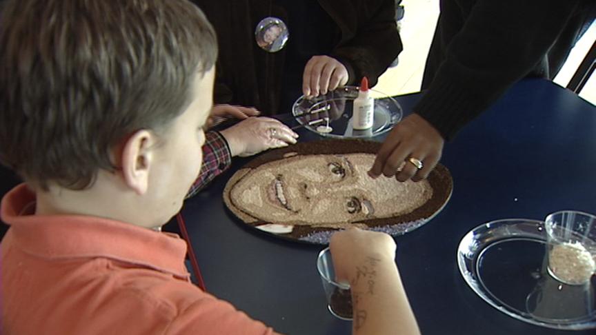 Caroline Bryant's son, Carter, helps decorate a picture of his mother made out of spices and seeds.