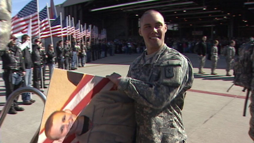 Pfc. Brent Thacker carries a poster of Spc. Kyle Palmer, who was diagnosed with Hodgkin's lymphoma about a month ago and must stay behind.
