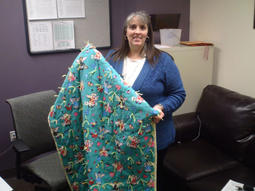 nstaCare manager Jana Rae Grose holds up one of the completed quilts.