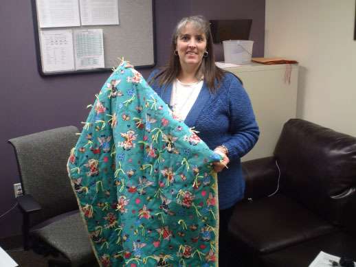nstaCare manager Jana Rae Grose holds up one of the completed quilts.
