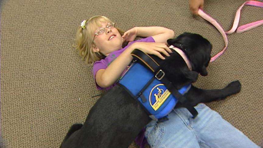 9-year-old Jordyn Pusey pets and plays with Gamee, a dog that is helping in Jordyn's treatment for autism.