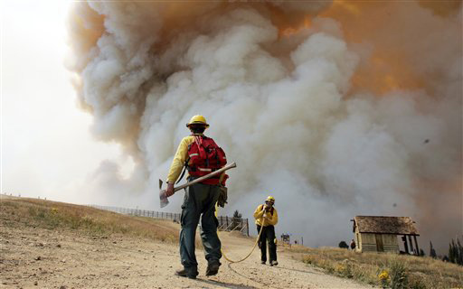 Firefighters move a hose as smoke from a wildfire rises, Tuesday, Aug. 28, 2007, in Ketchum, Idaho. Gusty winds stoked a wildfire above the central Idaho resort town, pushing flames near the border of the Sun Valley Resort ski area while air tankers and helicopters armed with red retardant made passes. (AP Photo/Elaine Thompson)