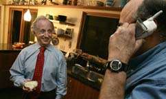 Mario Capecchi waits to be handed the phone from Lee Siegel for another interview while eating a piece of toast for breakfast Monday, Oct. 8, 2007, at his home in Salt Lake City.