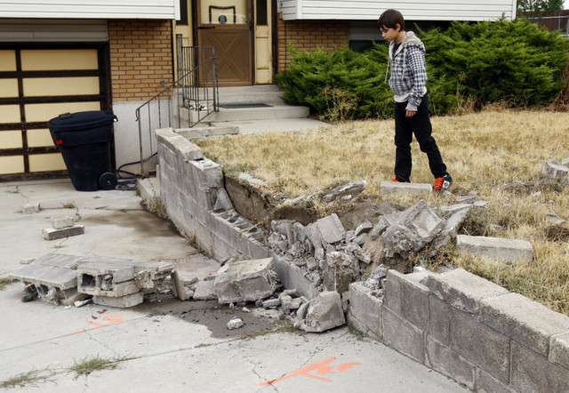 Ahi Transfield stands and looks over the broken retaining wall that the car smashed, he watched as a 13-year-old female driver hit and kill another 13-year-old female walking on the sidewalk just before school on Tuesday morning.(Scott G Winterton, Deseret News)