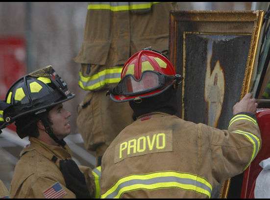 Provo Firefighters look at a painting of Christ that was burned in the fire. The fire burned the entire image except the image of Christ near the center. (Photo by Scott G Winterton, Deseret News)