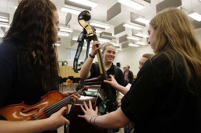 McKayla Porter, Jentree Hirsche, Mattie Racke (partially hidden) and Monica Christiansen admire a new bass donated by Fidelity Investments to Lakeridge Junior High School in Orem, Utah.