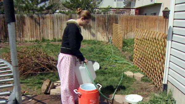 Annette Bell fills a water container at a neighbor's house.