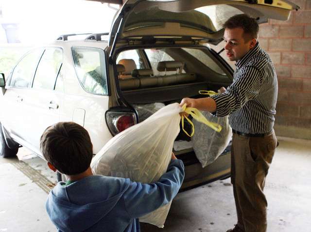 Lincoln and his father, Josh Ferrin, who recently closed on a new home, unloads bags of money and ammo boxes to turn over to Dennis and Kay Bangerter (not pictured), sons of the former owner at the home in Bountiful Wednesday, May 18, 2011. Ferrin found the stash of money in the attic over the garage, two hours after he took ownership of the home.