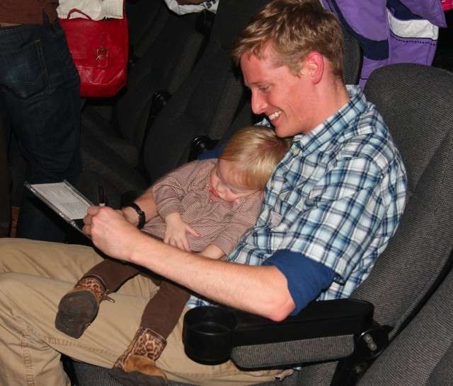 Keith Evans of Vocal Point signs an autograph while he holds the sleeping child of Vocal Point director James Stevens at the end of the party for "The Sing-off" Nov. 7.
