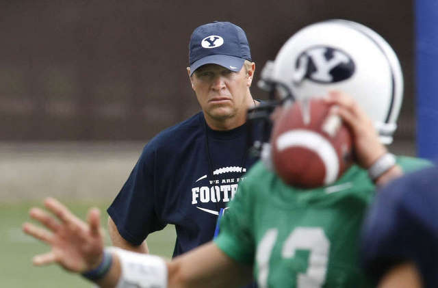 BYU head coach Bronco Mendenhall watches QB Riley Nelson throw a pass at practice.