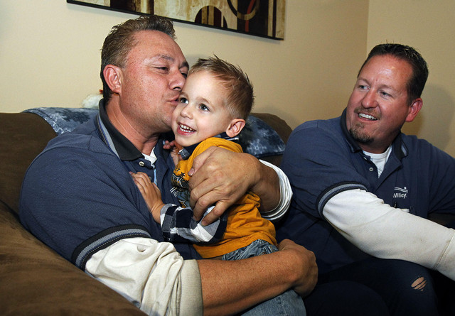 Fred Naeata gives a kiss to Kamden LaRose with Lee Parry at right, in Clinton, Tuesday, Dec. 20, 2011. The men, who are delivery associates for RC Willey, saved Kamden's life during a previous visit.