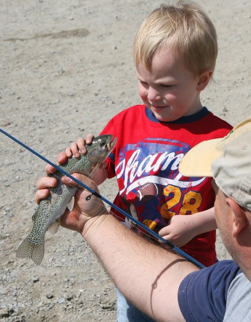 Grey Nielson, 3, carefully inspects the rainbow 
trout he just caught. (Photo: Flint Stephens)