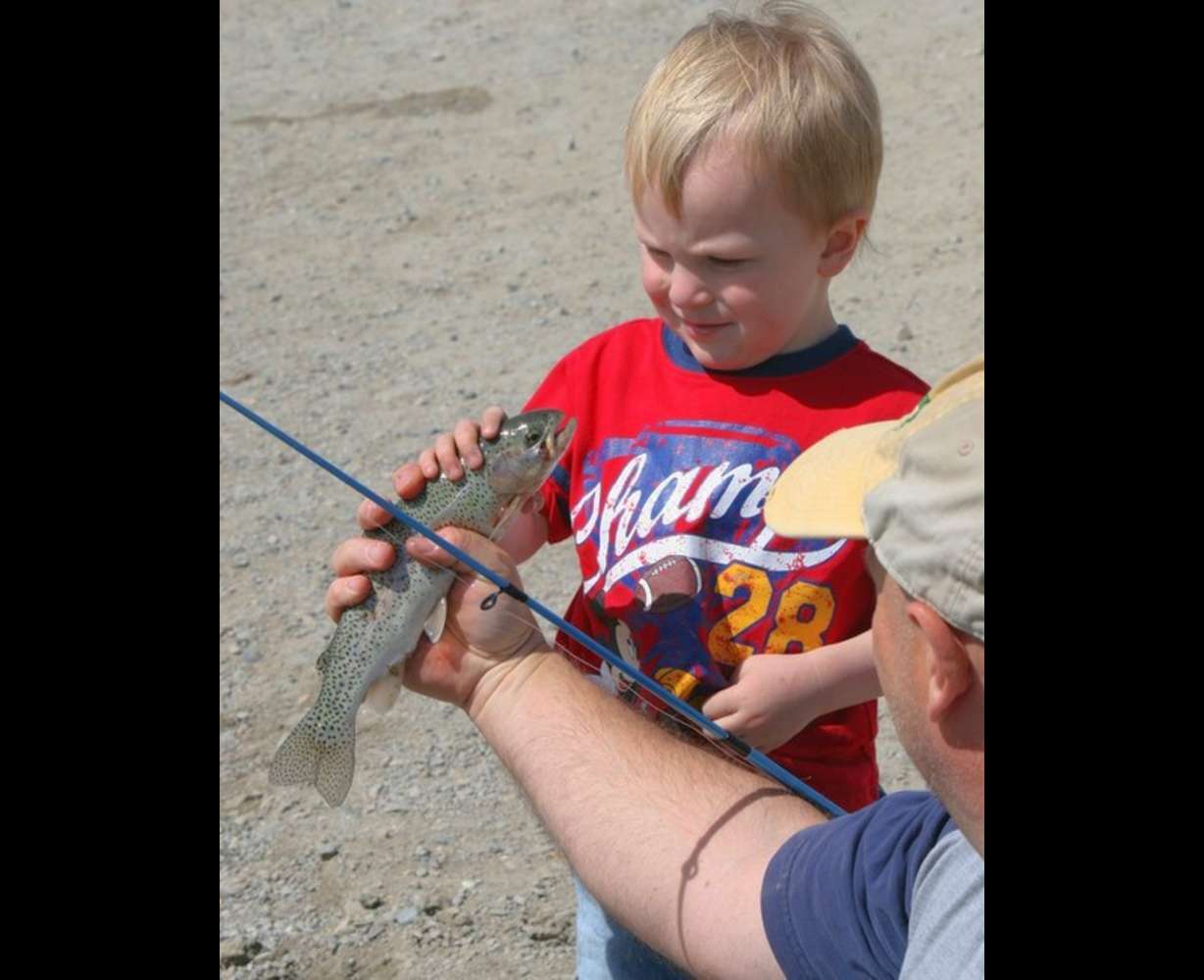 Grey Nielson, 3, carefully inspects the rainbow
trout he just caught. (Photo: Flint Stephens)