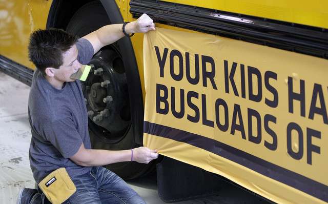 Jaren O'Farrell applies a wrap to a school bus in West Jordan Tuesday, April 24, 2012. The Jordan School District is wrapping several of its school buses with advertising. (Photo: Jeffrey D. Allred, Deseret News)