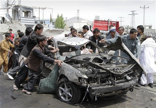 Afghans push a damaged car away from the scene of a militant attack in Kabul, Afghanistan, in May 2012. A suicide car bomber and Taliban militants disguised in burqas attacked a compound housing hundreds of foreigners in the Afghan capital officials and witnesses said. The Taliban said the attack was a response to President Barack Obama's surprise visit just hours earlier.
