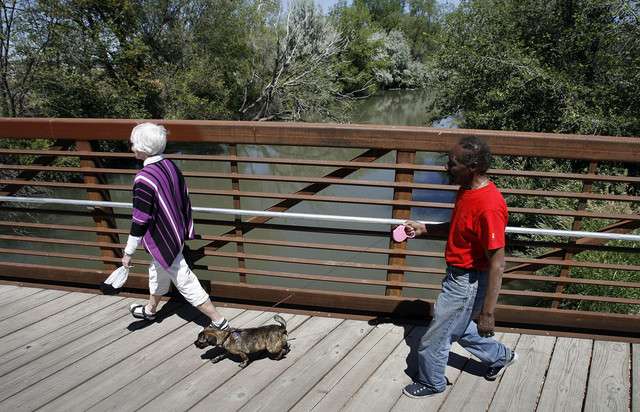 Leslie and Robb Benns, with their dog Sassy, cross a bridge as a new section of the Jordan River Parkway Trail is opened in Salt Lake City, Thursday, June 7, 2012.