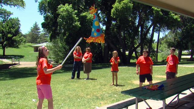 Children at the Kidstar Summer Camp for children with autism and their peer mentors gather around the piñata at their "unbirthday party" at Surgarhouse Park.
