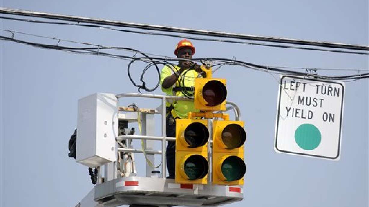 A Lynchburg City worker ties power lines above a traffic signal at Oakley and Memorial Avenues, July 1, 2012.