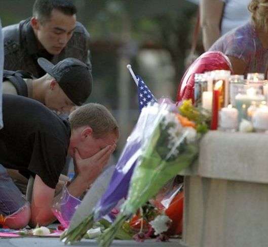 A man holds his face in his hands in front of a
memorial after a prayer vigil Sunday, July 22,
2012 in Aurora, Colo. Twelve people were killed
and over 50 wounded in a shooting attack early
Friday at the packed theater during a showing
of the Batman movie, "The Dark Knight Rises."
Police have identified the suspected shooter as
James Holmes, 24. (AP Photo/Alex Brandon)