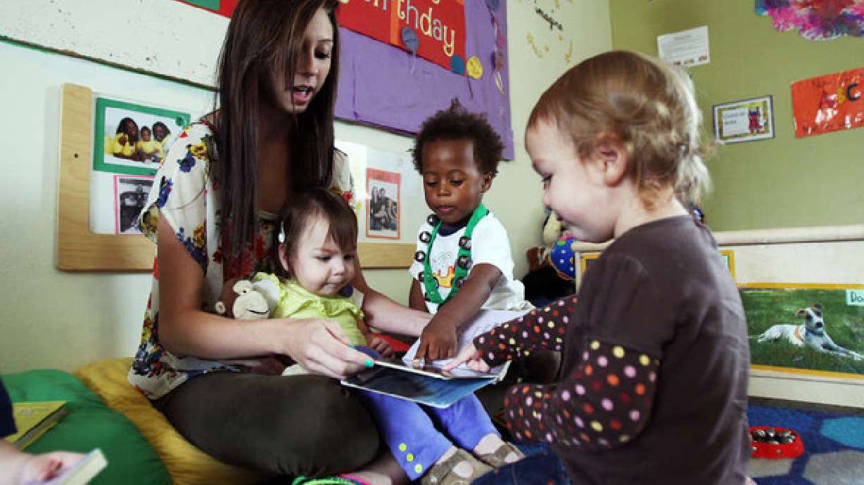 Brittany Palmer holds Isabella Uriarte and she reads to Je'Vanko Stewart and Lillian Jacoby, right, at the Wee Care Center at Utah Valley University in Orem on Sept. 24, 2012. A resurrected Utah bill aimed at increasing access to child care across the state prompted debate Monday about whether unlicensed home child care providers should be able to care for up to six children instead of four.