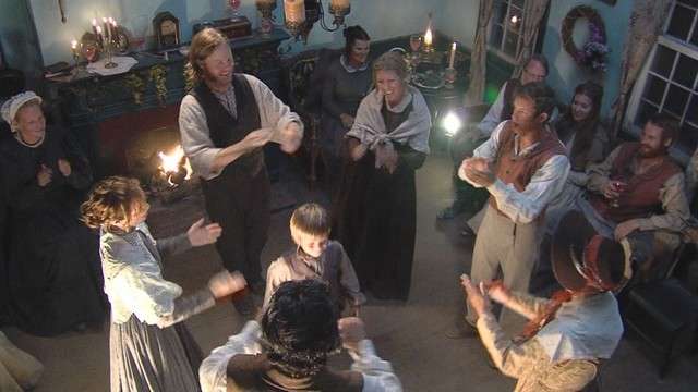 Extras dance during a party scene.