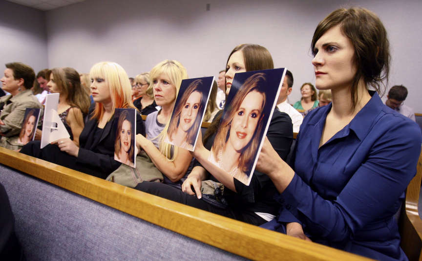 Family members of Martin Joseph MacNeill hold photos of Michele MacNeill up facing Mr. MacNeill as he makes his initial court appearance Monday, Aug. 27, 2012 in Provo.