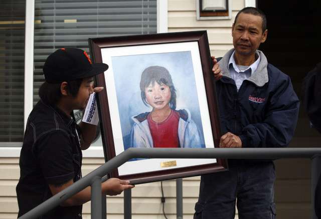 Kyi Kyi Po, left, and Cartoon Wah move a painting of Po's sister and Wah's daughter, Hser Ner Moo, during the Hser Ner Moo Community and Welcome Center Grand Reopening in Salt Lake City on Saturday, March 17, 2012. (Photo: Kristin Murphy, Deseret News)