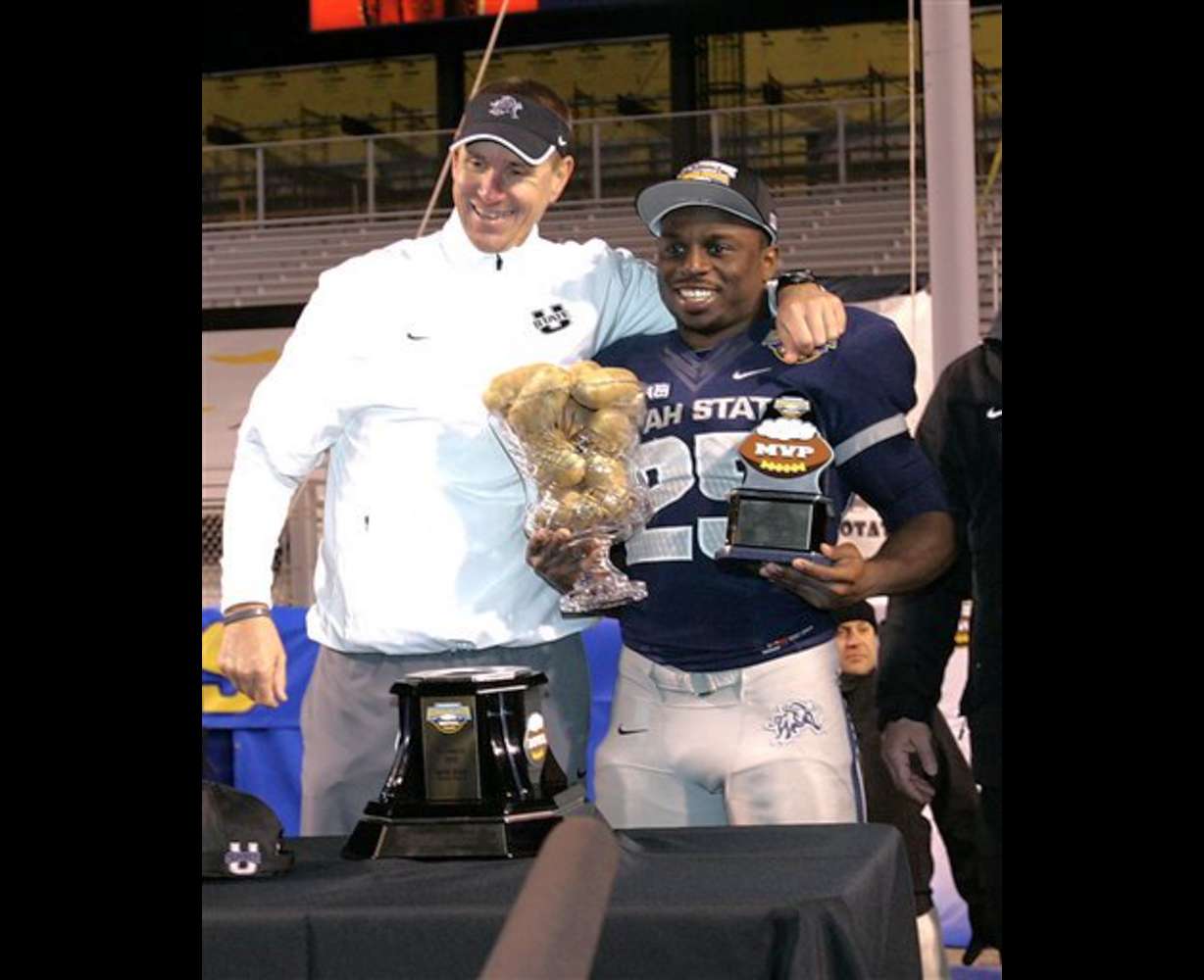 Utah State head coach Gary Andersen, left, and Kerwynn Williams (25) hold up the MVP award and the Bowl game trophy after an NCAA college football game against Toledo, Saturday, Dec. 15, 2012, in Boise, Idaho. Utah State defeated Toledo to win the Famous Idaho Potato Bowl game 41-15. (AP Photo/Matt Cilley)