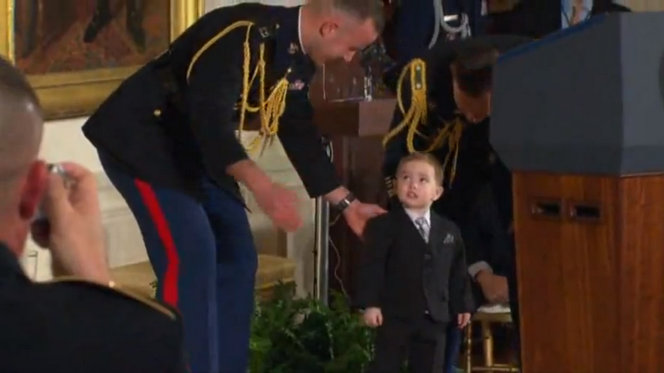 A presidential aid attempts to take little Colin Romesha off stage in the West Wing.