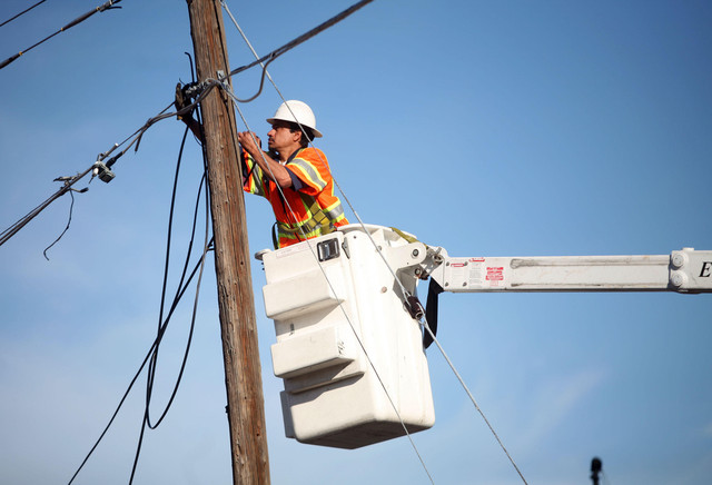 Ignacio Garcia fixes cable lines after a fire in Murray on April 4, 2013. U.S. land managers have given final permissions for a 416-mile transmission line that would connect wind farms in eastern Wyoming with customers in Utah and elsewhere across the West.