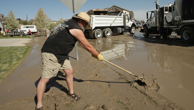 Mark Jackson cleans up Sunday, April 28, 2013, where several homes on Saddle Bluffs Drive were flooded Saturday when a canal breached.