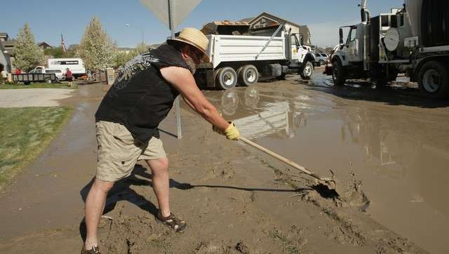 Mark Jackson cleans up Sunday, April 28, 2013, where several homes on Saddle Bluffs Drive were flooded Saturday when a canal breached.